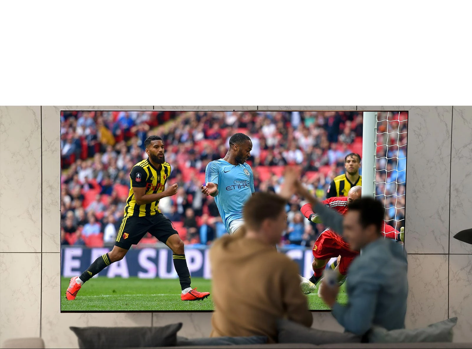 Des gens regardent un match de sport à la télévision dans le salon sur un écran de télévision ultralarge