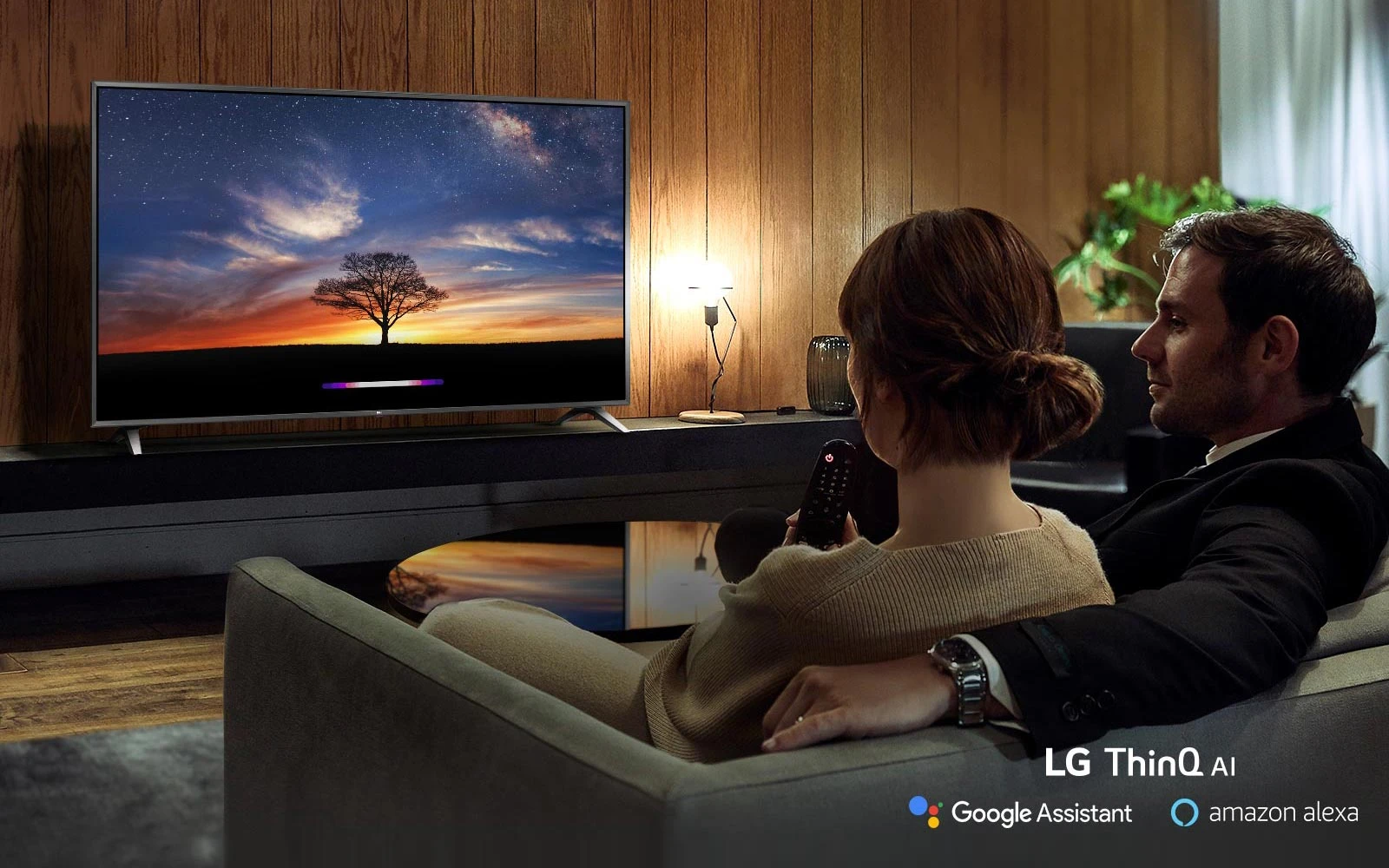 Couple utilisant l'Intelligence artificielle du téléviseur sans son canapé