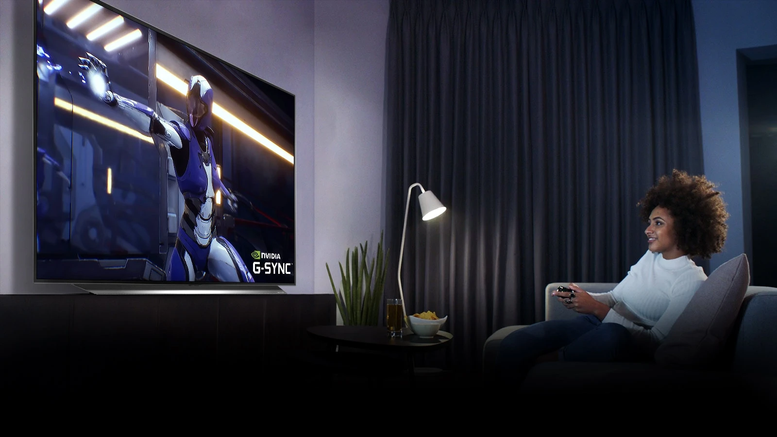 Femme assise sur un canapé, tenant un joystick tout en jouant à un jeu sur un écran de télévision
