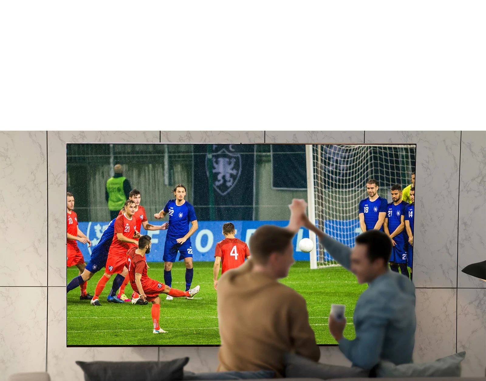 Les gens qui regardent un match de sport à la télévision dans le salon avec une très grande télévision à éboulis